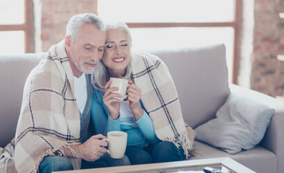 An older Owings couple wrapped in a blanket with warm drinks on a chilly day at home